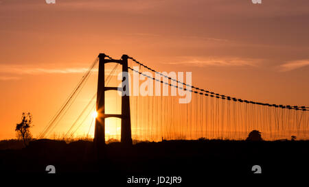 Alte Reste einer Hängebrücke bei Sonnenuntergang hinter sich. Stockfoto