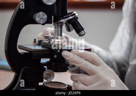 Ein junger Arzt Studie am Mikroskop, sorgfältig hält eine Kopie des dünnen Glases und unter die Linse platziert Stockfoto