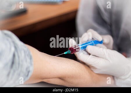 Arzt und Patient sitzt gegenüber von einander, während der Arzt eine Nadel herausziehen, das Blut des Patienten zu finden, bereitet Stockfoto