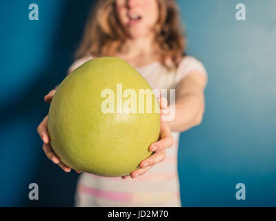 Eine junge Frau hält einen großen pomelo Stockfoto