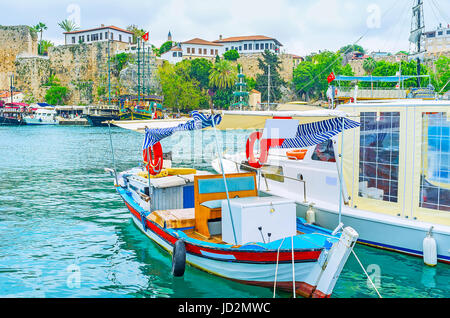 Der mittelalterlichen Stadtmauer von Antalya mit den osmanischen Häusern auf der Oberseite sind hinter dem Fischerboot im Hafen, Antalya, Türkei zu sehen. Stockfoto