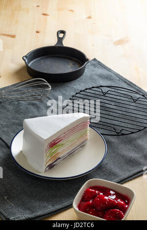 leckere Süßspeise Bäckerei Regenbogen Farbe Crêpe Torte mit frischer Erdbeersauce, selektiven Fokus Stockfoto