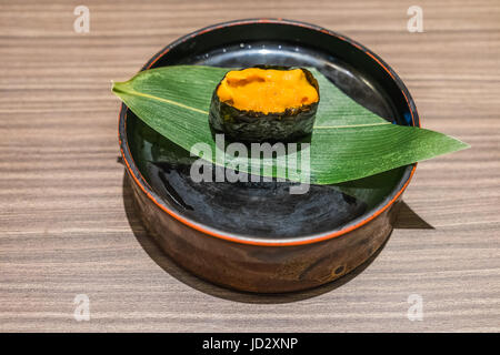 Uni Sushi japanisches Essen in schwarze Platte und Blatt auf Holztisch, Seeigel Stockfoto