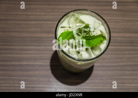 Eistee grünen Tee Latte und frischer Minze im Glas auf Holztisch Hintergrund Stockfoto
