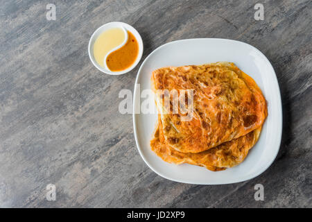 Indische Roti Prata mit Kondensmilch und Curry-Sauce, Nahaufnahme von rustikalen indischen Roti gebratenen Pfannkuchen Stockfoto