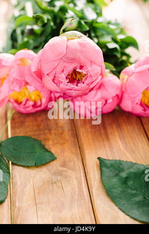 Liebe, Hochzeit, Romantik, Natur, Feier-Konzept - close-up der weiche rosa Pfingstrosen mit hellen gelben Kern gesammelt in wunderschönen Blumenstrauß auf Holztisch liegend Stockfoto