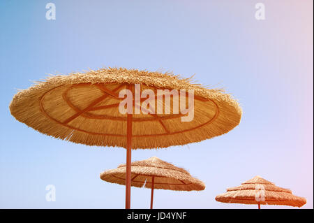 Zuckerrohr-Wicker-Strand-Sonnenschirme schließen gegen den Himmel bei sonnigem Wetter. Stockfoto