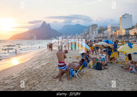 RIO DE JANEIRO - 27. Januar 2017: Strandbesucher am Strand von Ipanema lehnen Sie sich zurück in den Sonnenuntergang hinter zwei Brüder Berg nehmen. Stockfoto