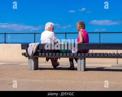 Zwei ältere Damen sitzen auf der Redcar Promenade genießen die Sonne an einem sehr heißen Sommertag. Stockfoto