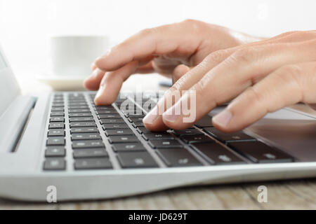 Hände, die schreiben auf einer Laptoptastatur im Büro in Nahaufnahme Stockfoto