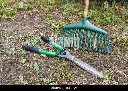 Gartenscheren und eine Harke auf einem Stück Garten von Unkraut gelöscht wird. Stockfoto