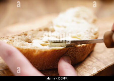 Junge, weibliche Hände ausbreitende Butter aufs Brot Stockfoto