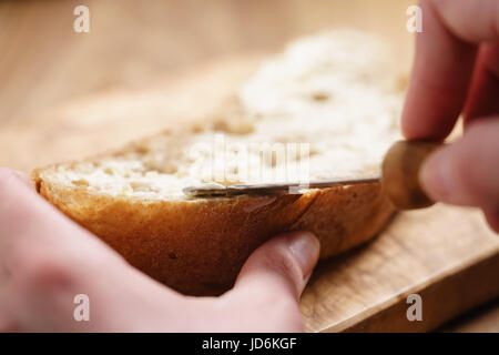 Junge, weibliche Hände ausbreitende Butter aufs Brot Stockfoto