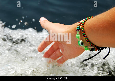 Weibliche Hand berühren schäumenden Wasserspritzer beim schweben auf Motor Boot. Nahaufnahme Bild. Stockfoto
