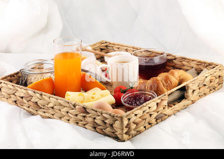 Frühstück im Bett mit Obst und Gebäck auf einem Tablett-Waffeln, Croissants, Kaffee und Saft Stockfoto