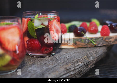 Fruchtwasser Gläser mit verschiedenen Zutaten präsentiert auf einem Baum-Datenträger Stockfoto