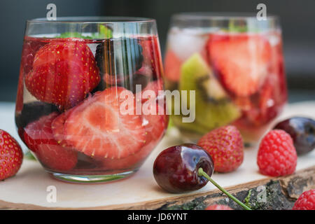 Fruchtwasser Gläser mit verschiedenen Zutaten präsentiert auf einem Baum-Datenträger Stockfoto