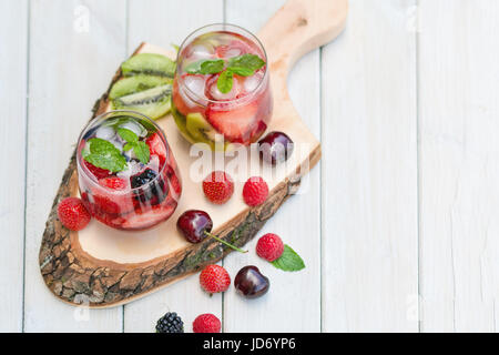 Fruchtwasser Gläser mit verschiedenen Zutaten präsentiert auf einem Baum-Datenträger Stockfoto