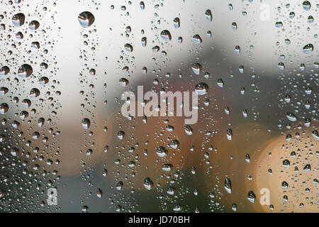 Wassertropfen auf einem Fenster gegen Stadt Ampel. Stockfoto