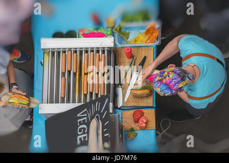 Erhöhte Ansicht des Kochens Grill. Verkauf und Service. Mann mit gesunde vegane Suppen, Wurst mit Soja-Protein-Wiener auf vegane Brötchen, Gemüse, selektiven Fokus. Stockfoto