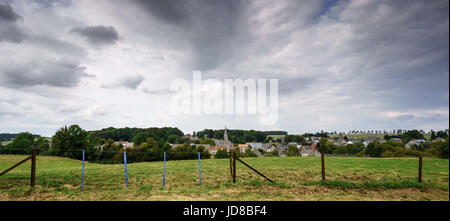 Panorama-Aufnahme des Zauns im Feld mit entfernten Gebäude und Wolken, Belgien. Belgien-Europa Stockfoto