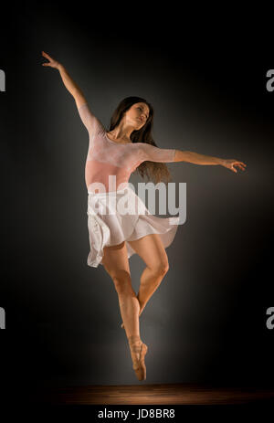 Weibliche Ballett-Tänzerin in der Luft mit Arme ausgestreckt, Studio gedreht. Kaukasische passen sportliche ziemlich mager Stockfoto