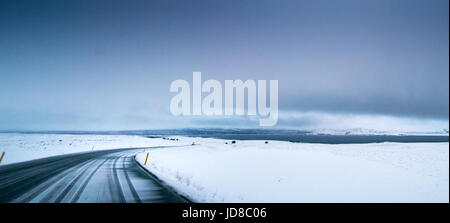 Düstere Schneelandschaft, Straßen- und stürmischen Himmel bei Tag, Island, Europa. Island-Natur 2017 Winterkälte Stockfoto