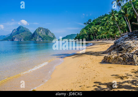 Sandstrand mit Palmen Schatten, riesige Felsen im Hintergrund, El Nido, Palawan, Philippinen. Stockfoto