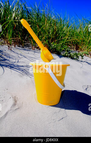 eine Schaufel und gelben Strand Eimer voller Sand am Strand Stockfoto