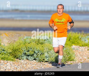 Mann Joggen entlang der Küstenstraße in den frühen Morgenstunden im Sommer an einem heißen Tag. Stockfoto