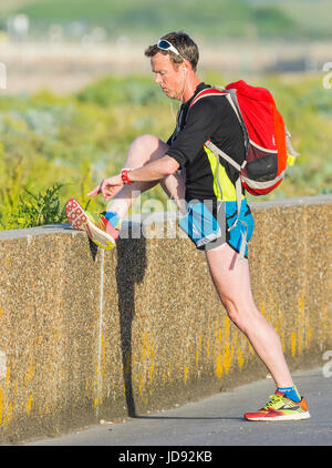 Mann, stretching und in den frühen Morgenstunden an einem heißen Sommern Morgen trainieren. Stockfoto