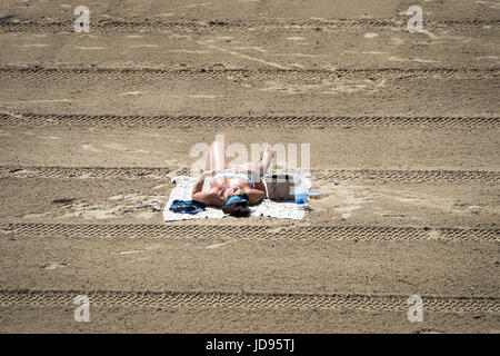 Sonnenanbeter am Strand von Barry Island, South Wales, wo Temperaturen in den hohen zwanziger Jahren sind und Menschen strömen in das Meer, das herrliche sonnige Wetter zu genießen. Stockfoto