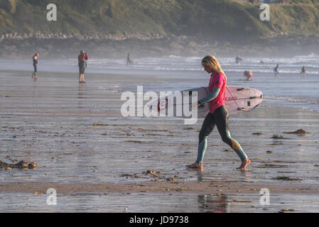 Eine Surferin zu Fuß aus dem Meer am Fistral Beach in Newquay, Cornwall Stockfoto