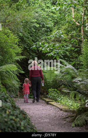 Eine Großmutter und ihre Enkelin zu Fuß entlang eines Pfades im subtropischen Trebah Garten in Cornwall. Stockfoto