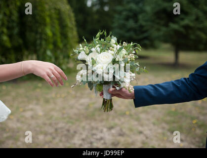 Bräutigam gibt der Braut eine schöne Hochzeit Bouquet. Stockfoto