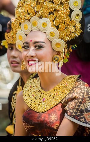 Elegante Porträt einer schönen balinesische Frau in extravaganten Bali Tracht gekleidet und lächelt in die Kamera. Atemberaubende goldene Kopfschmuck Stockfoto