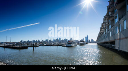 Blick über Wasser nach New York City mit Flugzeug-Trail in blauer Himmel, New York, USA. 2016 Großstadt Vereinigte Staaten von Amerika Stockfoto