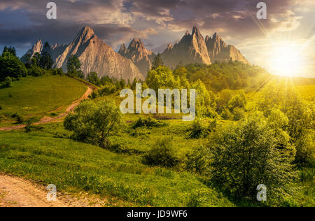 Zusammengesetzte Sommerlandschaft. Pfad durch den Wald auf grasbewachsenen Hügel in der hohen Tatra. schöne Sommerwetter mit blauen Himmel und einige Wolken am sunse Stockfoto