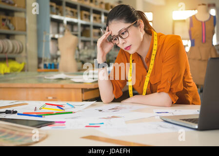 Schöne chinesische asiatische Frau ernsthaft nachdenken, wie man ein perfektes Produkt zu schaffen und tolle Idee des Designs in der Herstellung von Büro-Studio zu finden. professio Stockfoto