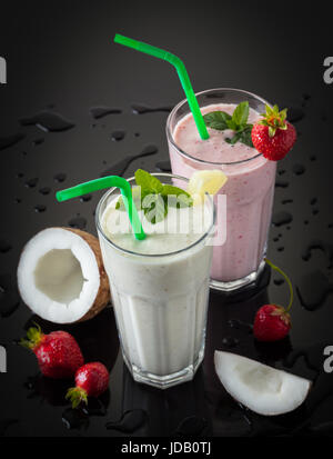 Milch-Shakes mit Früchten auf einem schwarzen Hintergrund und Wassertropfen Stockfoto