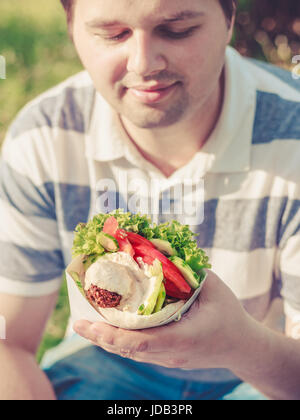 Mann hält Falafel Sandwich in Papiertüte. Gesund Street Food-Konzept, orientalische Küche. Selektiven Fokus auf Nahrung Stockfoto