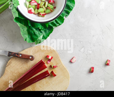 Frische Bio Rhabarber Schäfte mit Zuschnitte in Metallschale über grauen Beton Stein Hintergrund Stockfoto