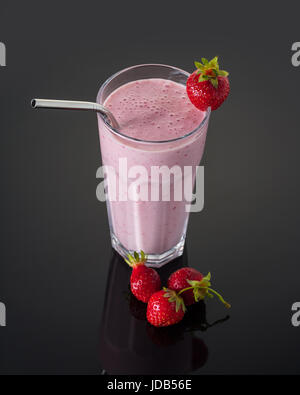 Milchshake mit Erdbeeren in einem Glas auf schwarzem Hintergrund Stockfoto