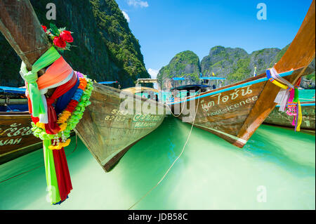 KRABI, THAILAND - 12. November 2014: Traditionelle Thai Longtail Boote geschmückt mit viel Glück Bogen Schärpen Schwimmer im Vordergrund Stockfoto