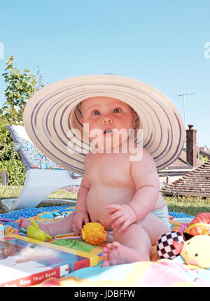 Niedliche 6 Monate altes Baby Mädchen Hut eine Erwachsene weibliche Sonne im Garten Foto von Simon Dack Stockfoto