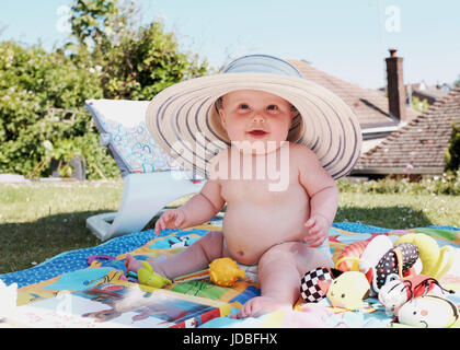 Niedliche 6 Monate altes Baby Mädchen Hut eine Erwachsene weibliche Sonne im Garten Foto von Simon Dack Stockfoto