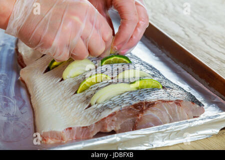 Marinierte gebratene Fisch braten mit Gewürzen n Zitrone filets in Öl mit Zitrone und Zwiebel Teller im Ofen Stockfoto