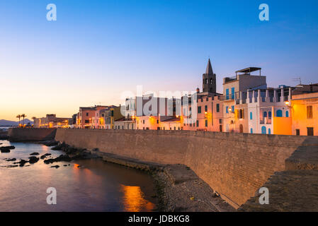 Alghero Stadtbild Dämmerung, einen Blick auf die Skyline der alten Stadt in Alghero an einem Sommerabend mit der großen mittelalterlichen Ufermauer im Vordergrund, Sardinien. Stockfoto