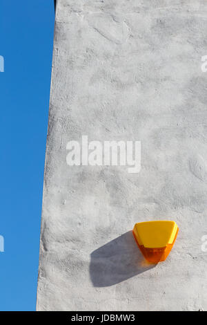Gelbe Alarmanlage Kasten auf eine weiße Wand, gegen den blauen Himmel. in England. Stockfoto
