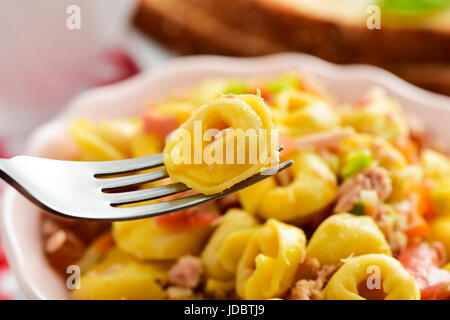 Nahaufnahme von einer Keramikschale mit einer Pasta Salat mit Tortellini auf einem Tisch zum Mittag- oder Abendessen Stockfoto